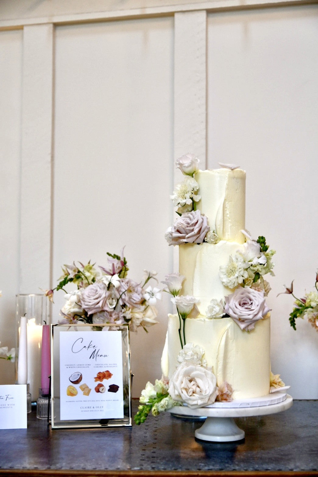Three-tiered wedding cake with floral decorations on a wooden table.